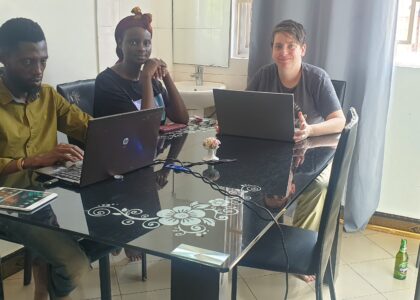 Three people working on laptops around a dining table.